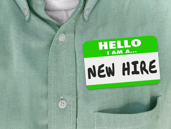 New Hire nametag on a green shirt worn by a new employee or fres