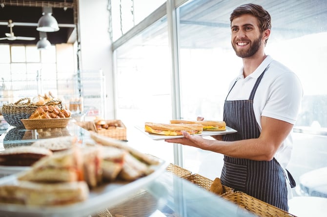 happy worker holding sandwiches at the backery