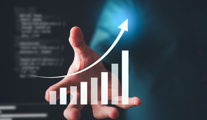 Business owner's hand presenting a rising bar chart with an upward arrow, representing KPIs for company vision trending toward long-term growth