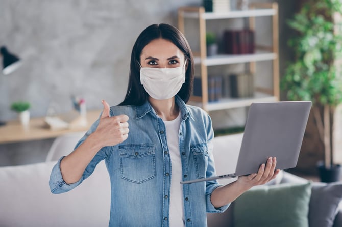 Woman wearing a Face Mask holding a Lap Top