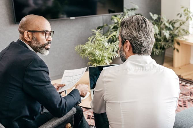 Two business leaders reviewing performance documents during a one-on-one management meeting